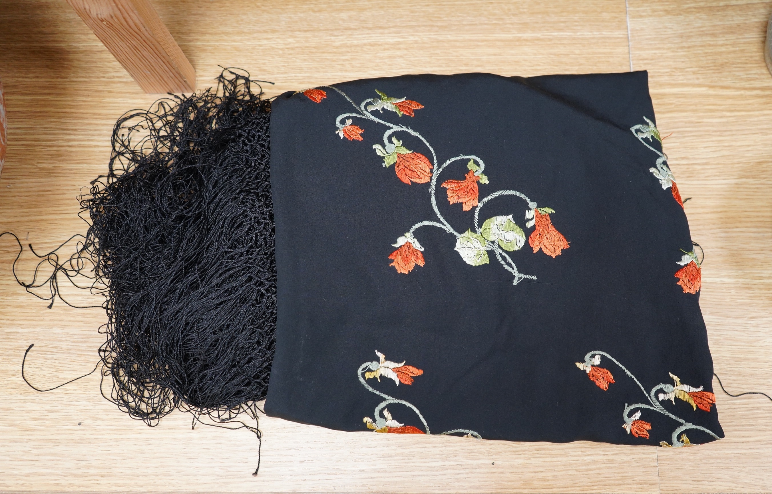 A black silk embroidered shawl with orange yellow and green polychrome embroidery to one corner, edged with long silk fringe. Condition - fabric good, some marks to silk may possibly sponge off